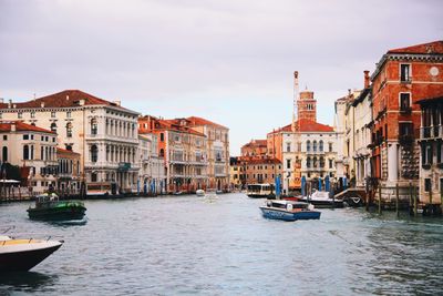 Boats in canal amidst buildings in city