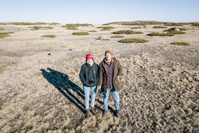 Portrait of couple standing on field against clear sky