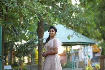 Portrait of smiling young woman standing against trees