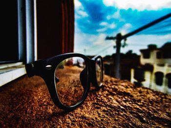 Close-up of sunglasses on glass against sky