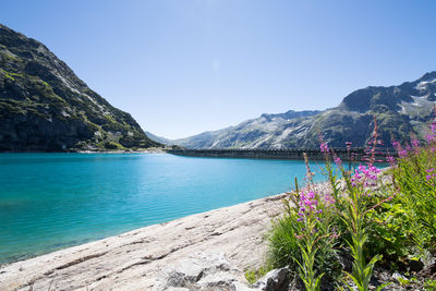 Scenic view of lake and mountains against clear blue sky