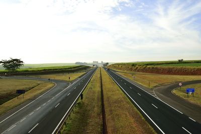 Road amidst field against sky