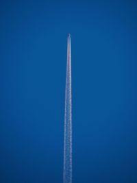 Low angle view of airplane flying against clear blue sky