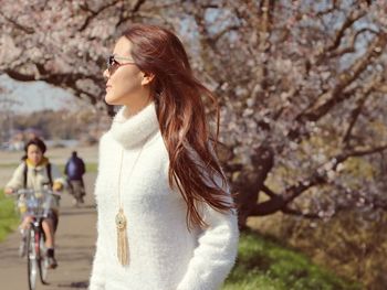 Side view of young woman against tree