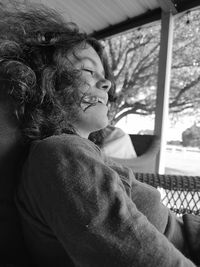 Side view of woman looking through window