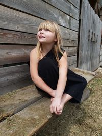 Young woman looking down while sitting on wood