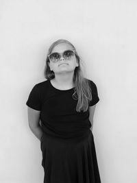 Portrait of young woman wearing sunglasses against white background