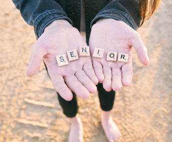 Low section of woman showing alphabet blocks on beach