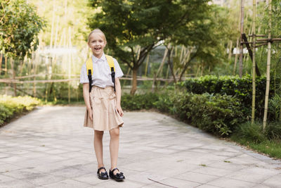 Back to school. little girl with yellow backpack from elementary school outdoor