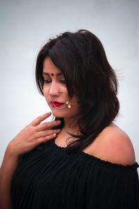 Thoughtful woman wearing nose ring against wall