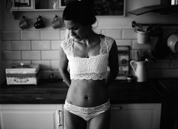 Woman in lingerie standing at kitchen