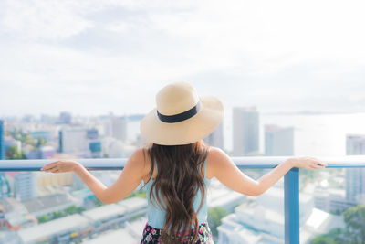 Rear view of woman standing against sky in city