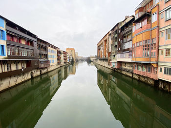 Canal amidst buildings in city against sky