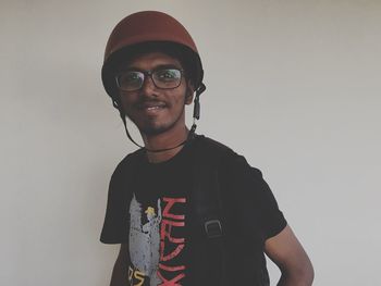 Portrait of young man wearing helmet against white background