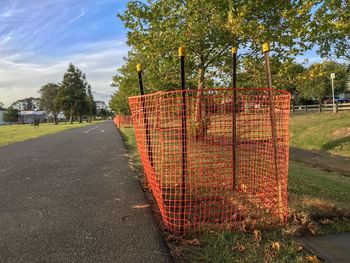 Road by fence on field against sky
