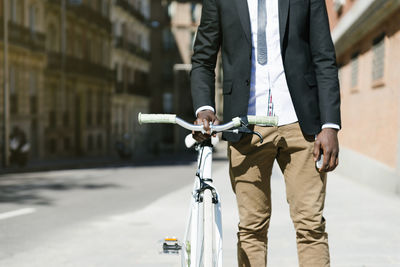 Midsection of man with bicycle standing on street