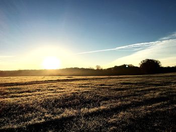 Sun shining through clouds over field