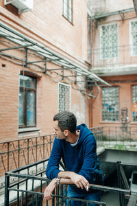 Full length of young man looking through window in building