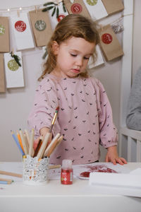 Toddler child writing christmas letter and doing advent calendar tasks in kids room. festive