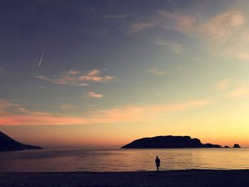 Silhouette of people looking at sea against sky during sunset