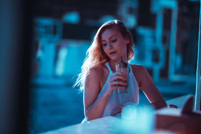 Young woman having drink while sitting at cafe