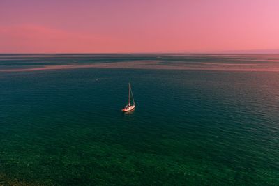 Sailboat sailing on sea against sky during sunset