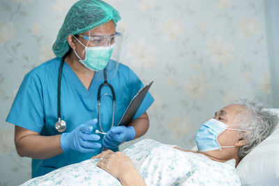 Doctor wearing mask examining senior patient at hospital