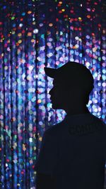 Rear view of silhouette man against illuminated lights