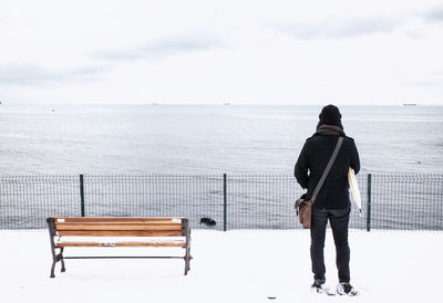 Rear view of man standing by sea against sky