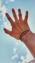 Low angle view of human hand against sky