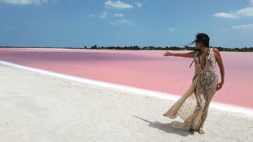 Woman standing on beach against sky