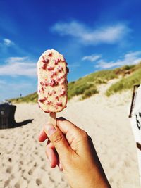 Midsection of person holding ice cream cone on beach