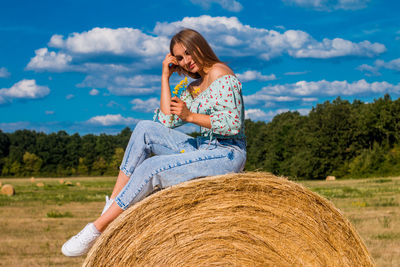 Side view of woman sitting on hay