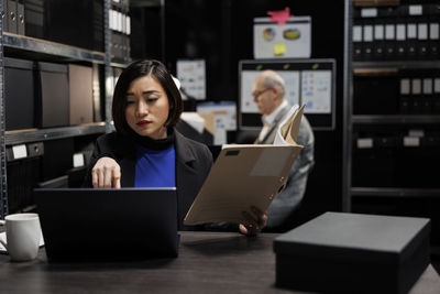 Young woman using laptop while sitting in office