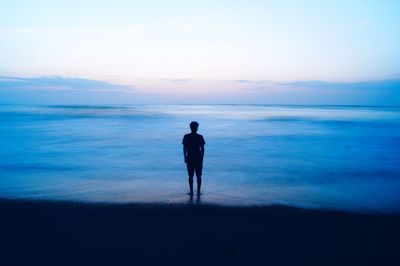 Silhouette man standing at beach during sunset