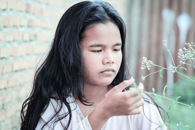 Girl looking at flowering plant in lawn