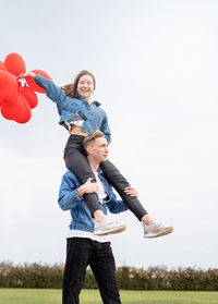 Valentines day. young loving couple hugging and holding red heart shaped balloons outdoors