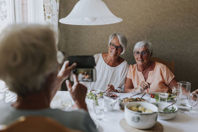 Senior women having picture taken while having meal together