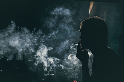 Rear view of silhouette woman standing against black background