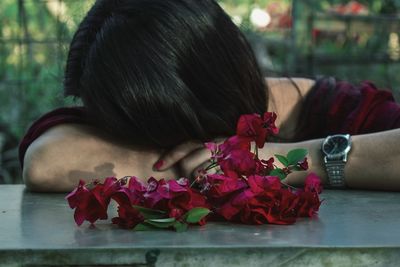 Close-up of pink bougainvillea against woman resting on table