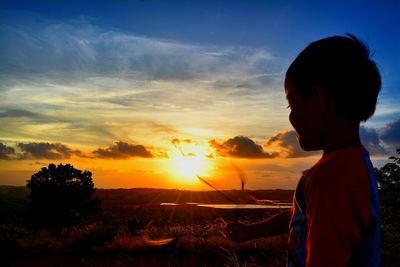 Silhouette woman standing by tree against sky during sunset