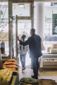 Full length rear view of father and daughter leaving fashion boutique