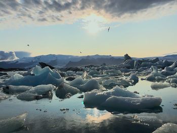 Scenic view of frozen lake against sky during sunset