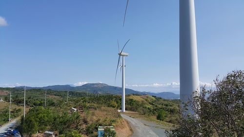 Windmills on landscape against blue sky