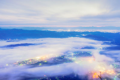 Aerial view of illuminated mountains against sky during sunset