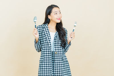 Portrait of smiling woman standing against gray background