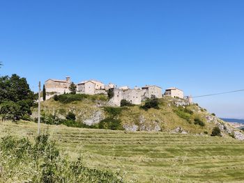 Buildings on field against clear blue sky