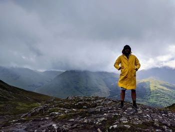 Man wearing raincoat while standing on mountain during rainy season