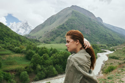 Portrait of young woman standing against mountain