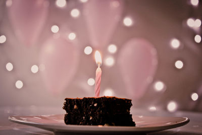 Close-up of lit candle on cake